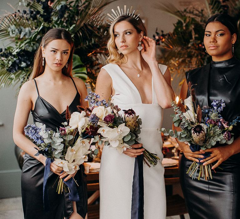 Bridal party holding moody dark wedding flowers bouquets with closed king proteas, orchids and roses 