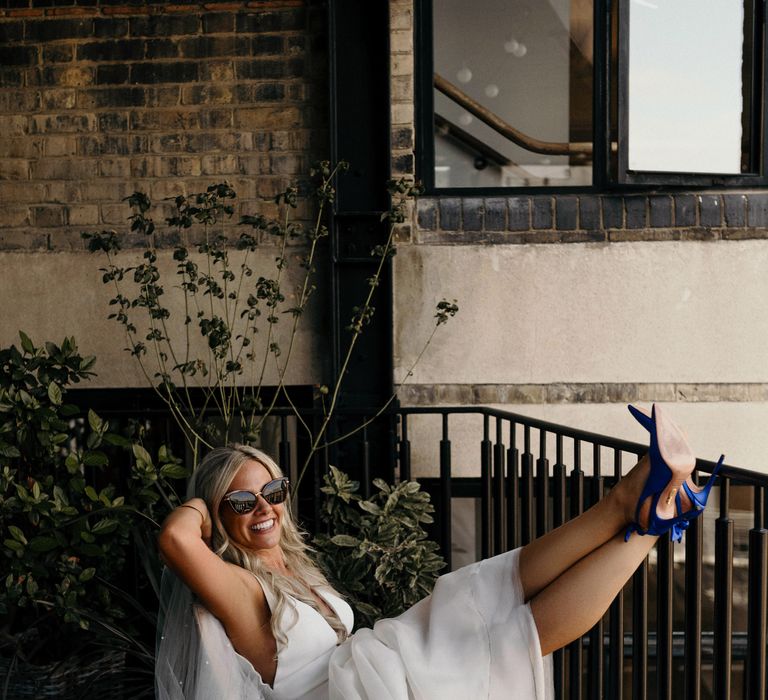 Bride sits with her legs up wearing blue satin pumps