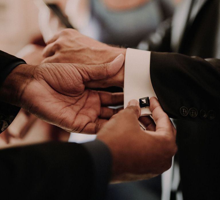 The groom fastening his cuff links