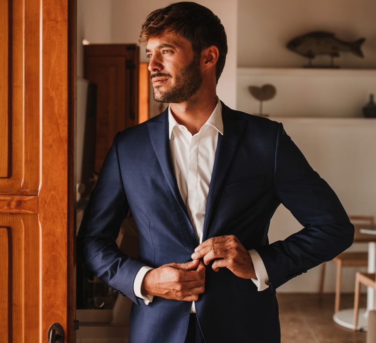 Stylish groom in a white shirt and navy suit 