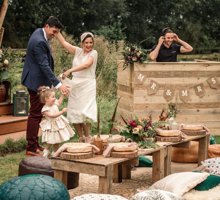 Bride & groom dance outdoors with DJ in wooden booth