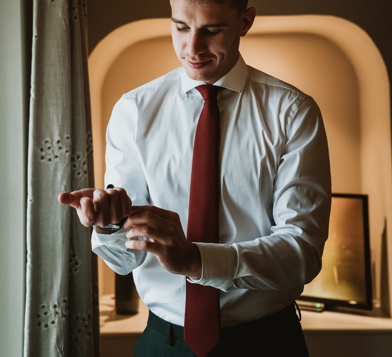 Groom does up cufflinks on his wedding day