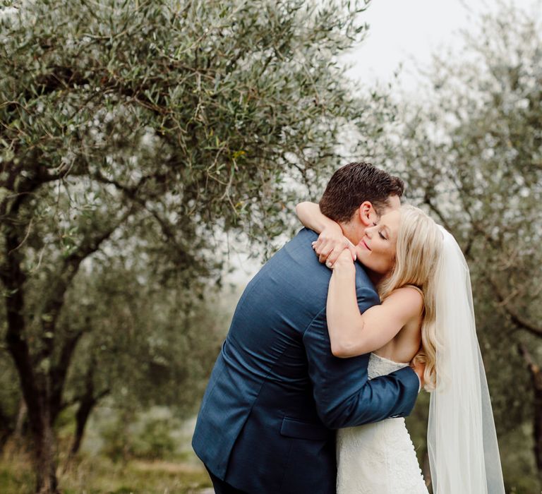 The bride and groom hug in an olive grove at their Italy elopement