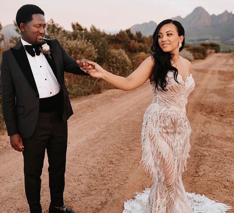 Groom in a tuxedo twirling his bride around in a Biji La Maison de Couture wedding dress with feathers