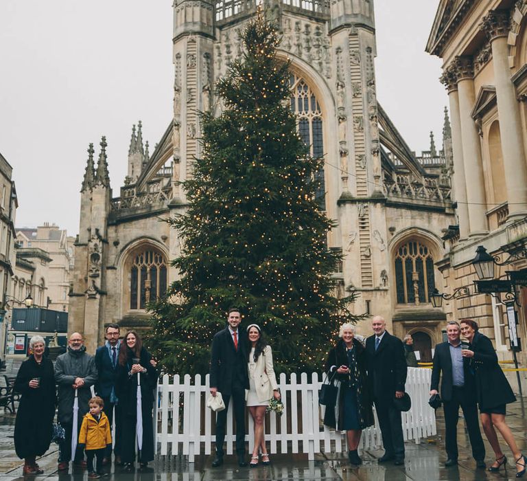 Bride and groom stood in front of Christmas tree in bath