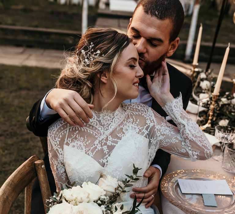 Bride in a lace bodice wedding dress with long sleeves holding an all white rose wedding bouquet 