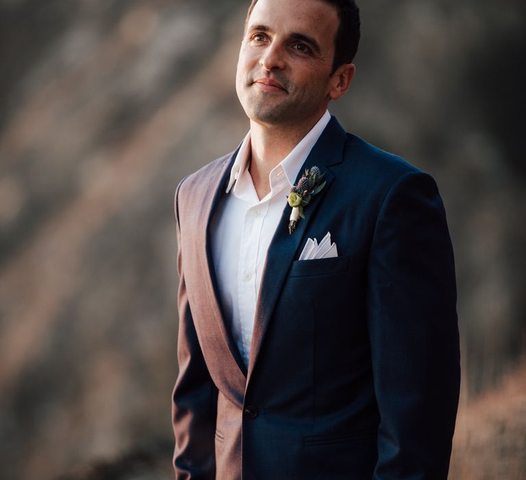 Groom wears blue suit with open white shirt