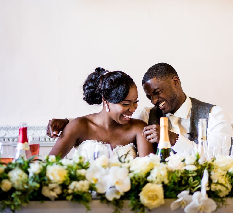 Bride & groom look lovingly at one another in front of floral displays on their wedding day