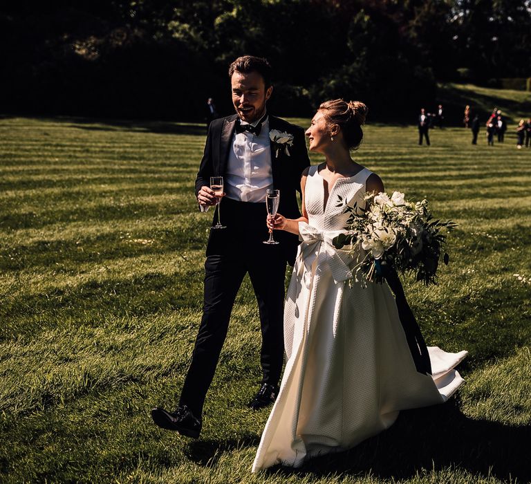 Bride & groom walk through manicured gardens on their wedding day