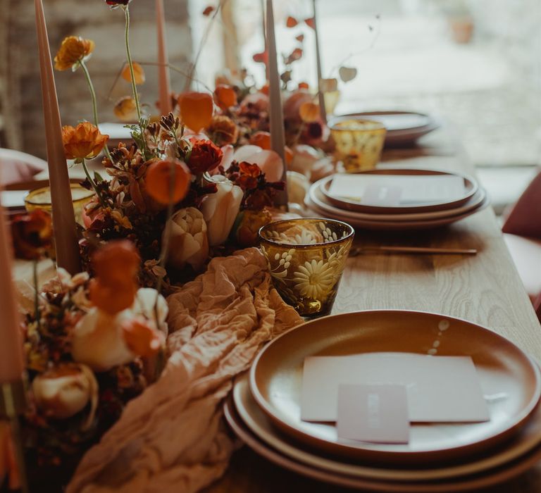 Beautiful orange tone wedding flowers and linen table runner