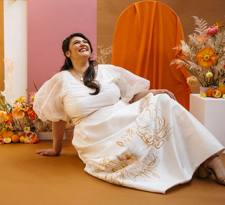 Bride sitting on the floor and laughing in her wedding separates by Paper To Lace