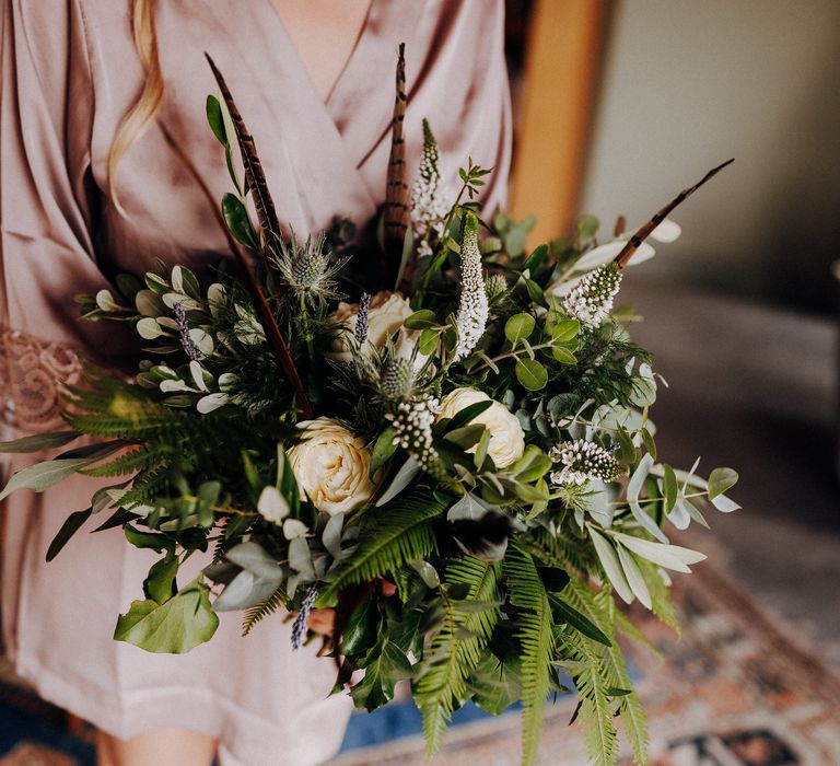 Bridal bouquet filled with white florals, greenery and feathers