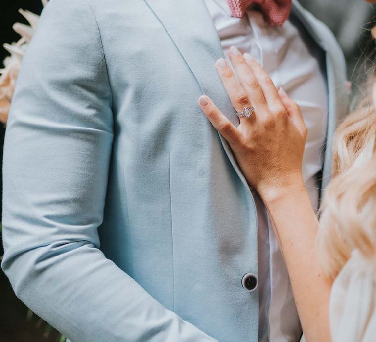 Bride places her hand on grooms pale blue suit blazer