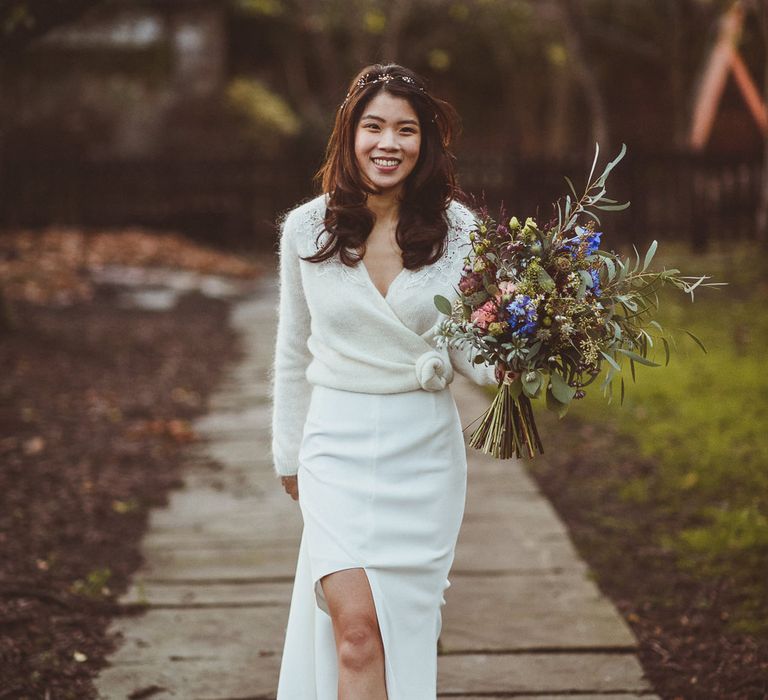 Beautiful East Asian bride in a fitted wedding dress and a wrap cardigan with lace and rosette detail 