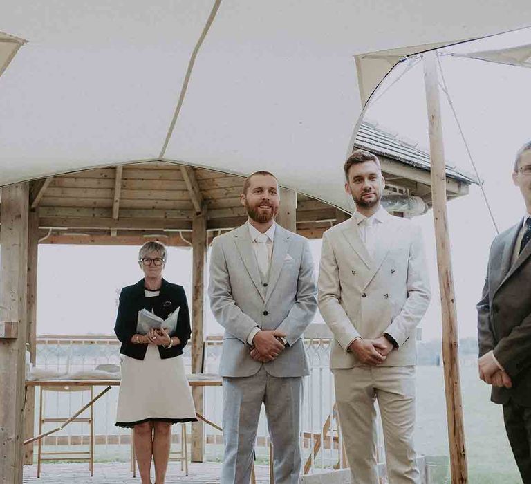 Groom watches bride walk down the aisle at outdoor ceremony