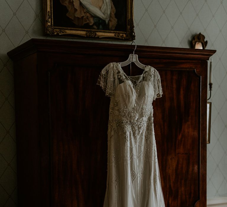 Vintage inspired embellished wedding dress hanging on a wardrobe 