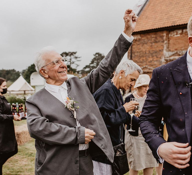 Wedding guest throws confetti over groom