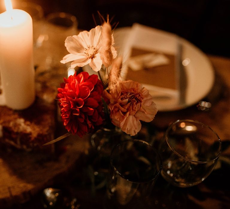 Rustic wedding table with pink florals, lit candle and foliage table garland