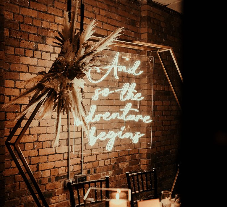 Sweetheart table with metal hexagon backdrop, neon sign and dried flower decor 