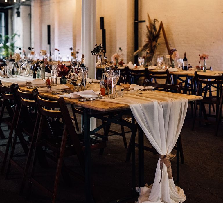 100 Barrington wedding reception with fairy lights, chiffon table runner and flower stems in bottles 