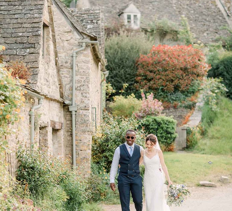 Bride & groom walk hand in hand through the Cotswolds 