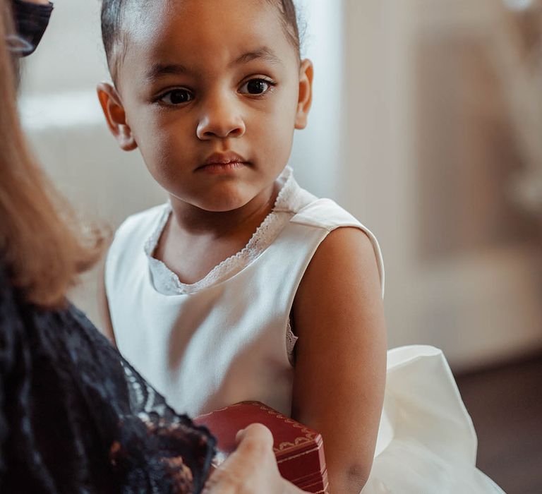 Flower girl wears hair in a bun and white tea length dress