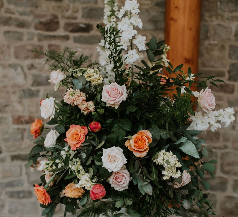 Pink and orange rose wedding flower arrangement on display at the reception