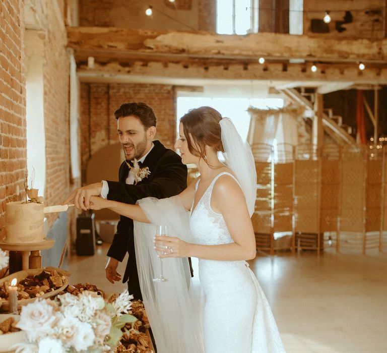 Bride and groom cut their single tier pink and white buttercream frosted wedding cake