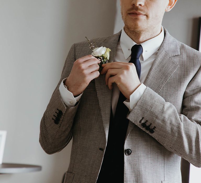 Groom in puppy tooth suit, navy blue tie and white rose buttonhole