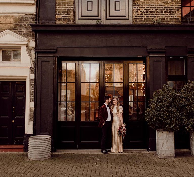 Bride and groom stand together in London city near their industrial wedding venue