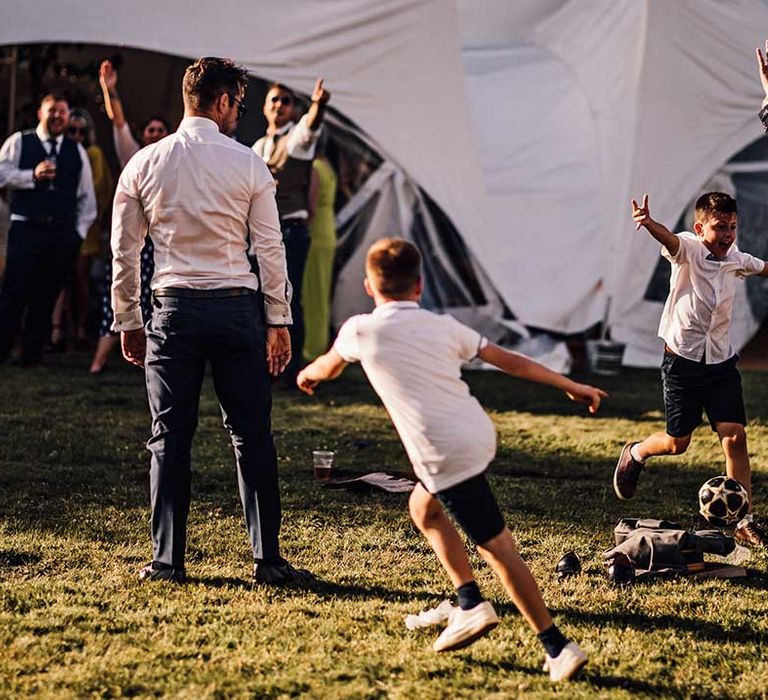 Wedding guests and children play a game of football before the wedding breakfast 