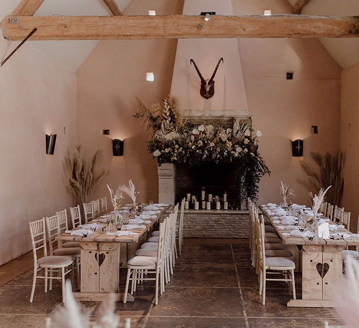 Rustic reception venue with wooden banquet tables complete with muted tones and dried florals 