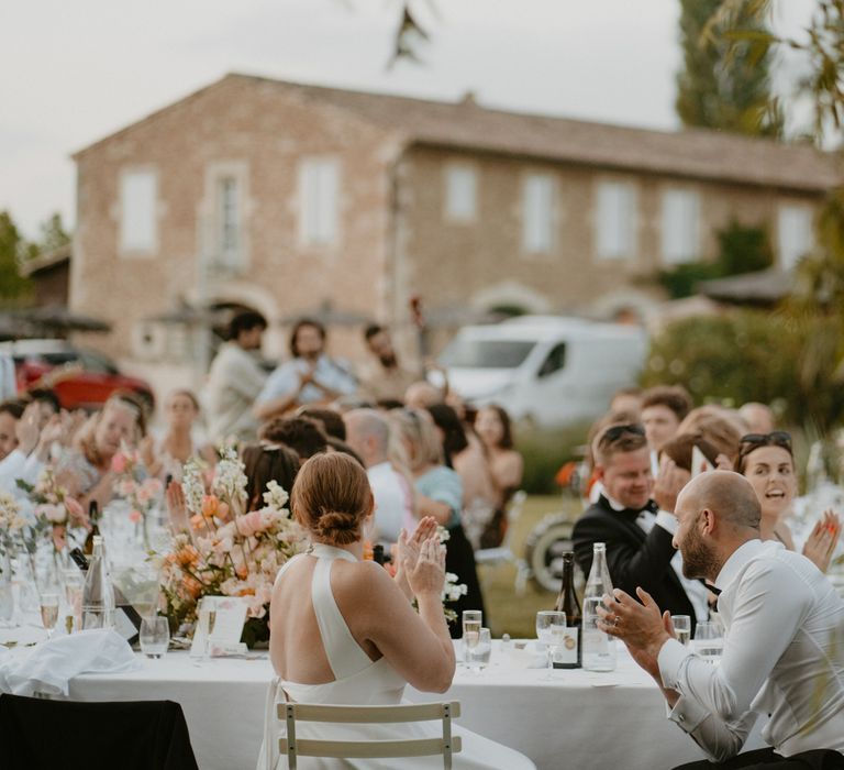 Bride & groom outdoors during wedding reception in Mas Loisonville with banquet tables and white tablecloths with pale pink floral arrangements