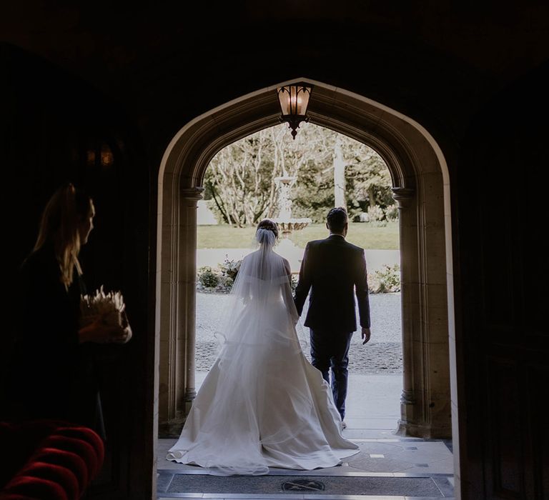 Bride and groom walk through the exit of Maften Hall as a married couple