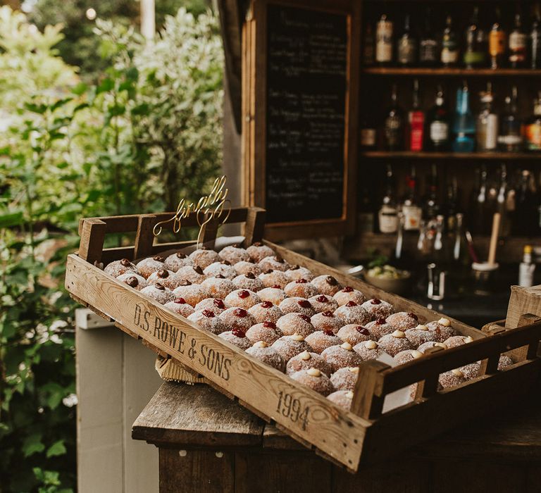 Filled doughnuts wedding favours in a wooden crate on the bar 