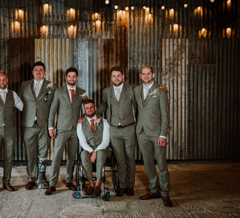 Groom party in matching three piece grey suits, with the groom in burnt orange tie, pocket square and boutonniere