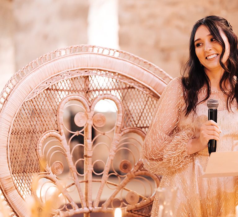 Bride gives bridal speech on her wedding day in front of sweetheart chairs