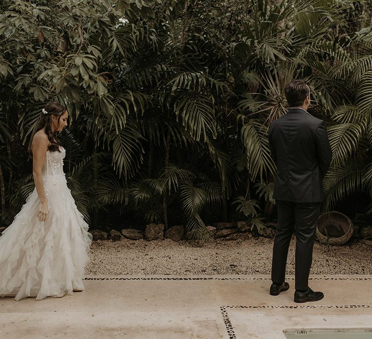 Bride approaches her groom during first-look moment outdoors 