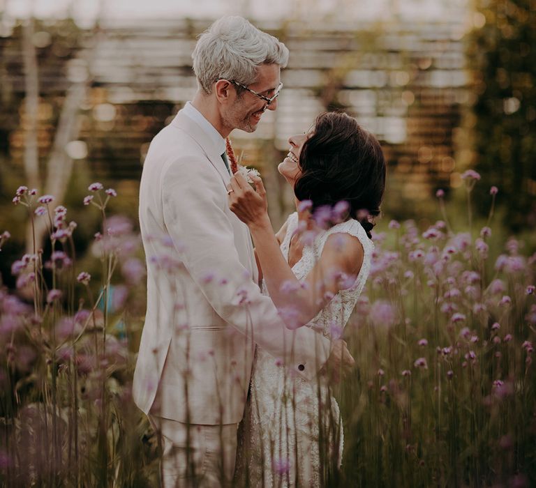 Bride and Groom holding each other and laughing in a field of tall purple flowers