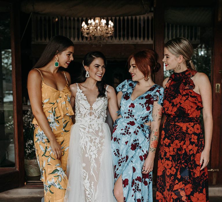 Bridesmaids in different colour floral bridesmaid dresses with the bride in a lace wedding dress 