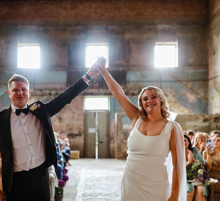 Bride wears pearl embellished cape whilst holding her grooms hand at The Asylum 