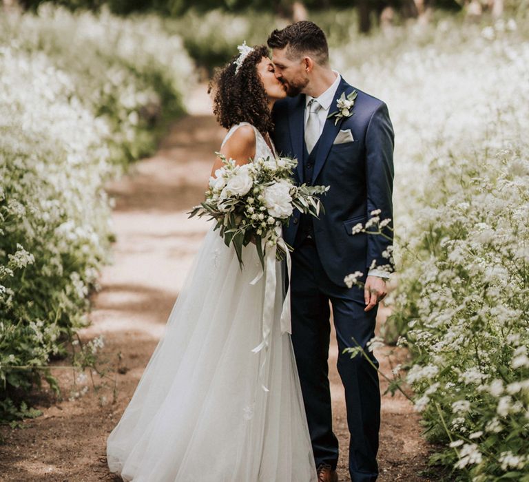 Bride embraces her groom outdoors during couples portraits 