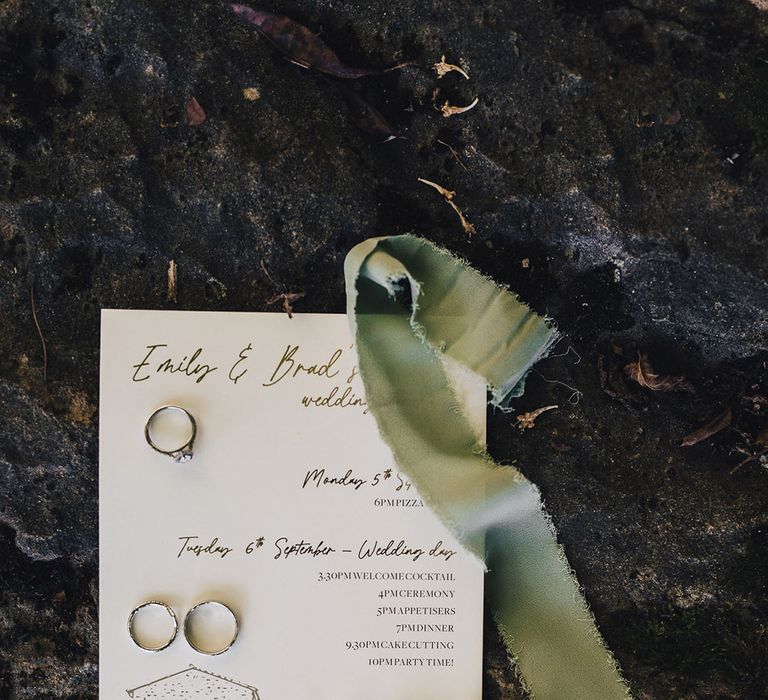 White wedding stationery beside green ribbon and pearl drop earrings