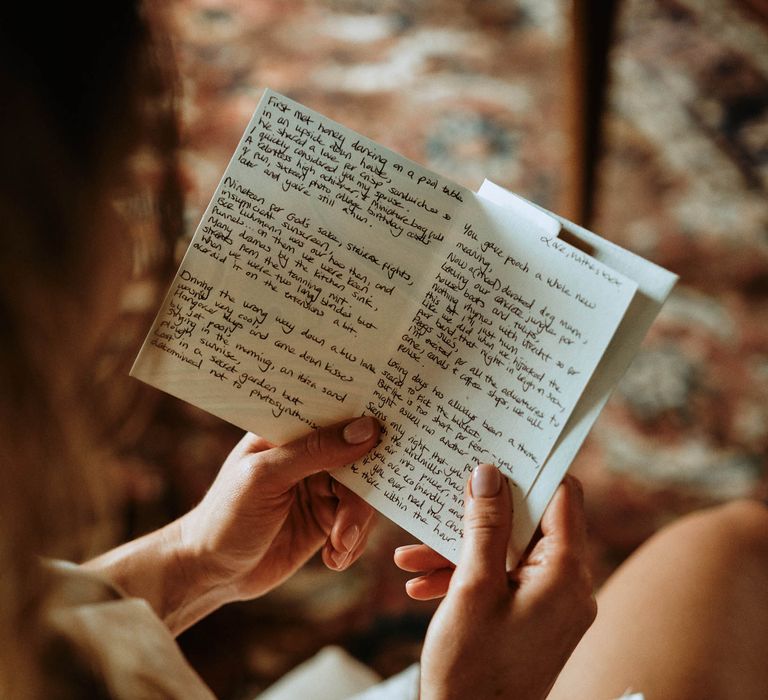 Bride reading letter from groom on the morning of the wedding whilst in bridal pyjamas