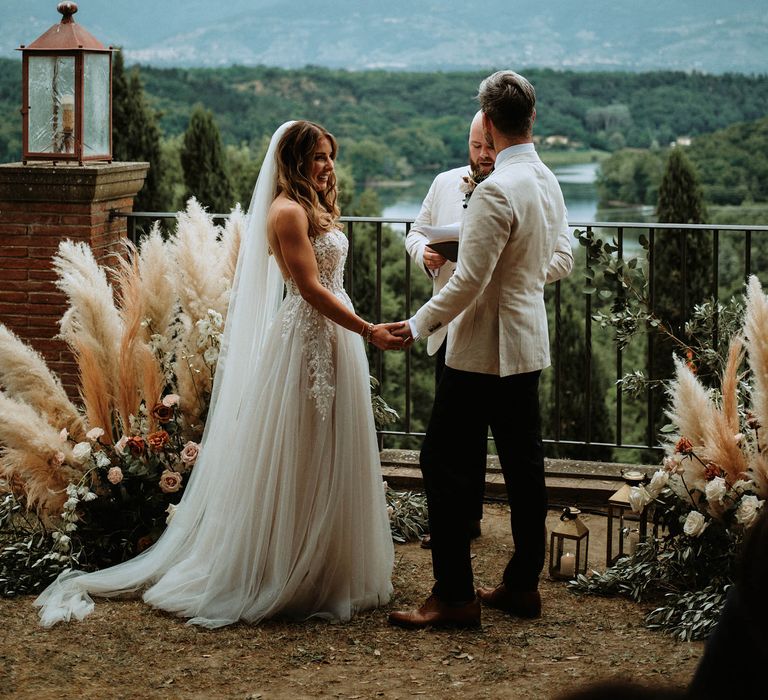 bride and groom at altar decorated with pampas grass at Italian destination wedding in Tuscany