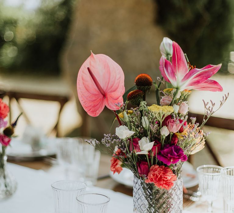 floral centrepiece cosisting of pink Anthurium, Oriental Lillies, coral Carnations, magenta Peonies and wildflower in a crystal vase