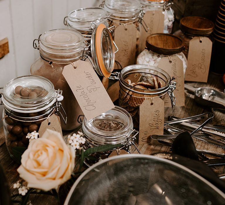 Wedding hot chocolate station with waffles, marshmallows, and other toppings in glass jars 