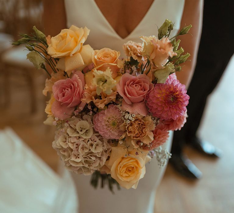 Bride holding pink and orange roses with gypsophila bouquet 