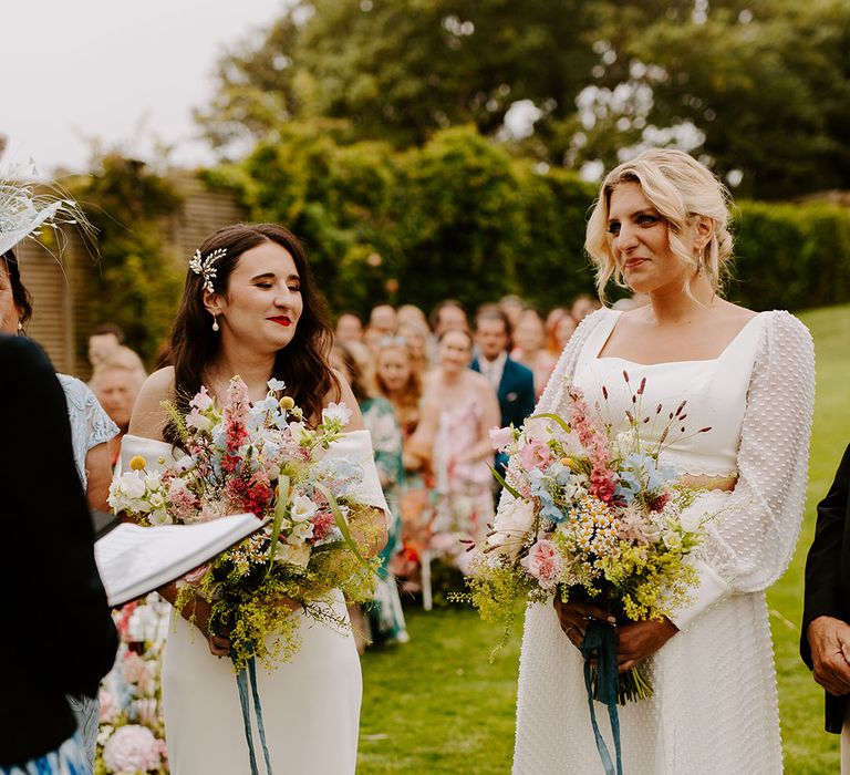 Bride wearing a spotted long sleeve bridal two piece with another bride in off the shoulder wedding dress for lesbian wedding 