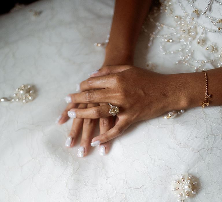 Bride with pearl wedding nails wearing a canary yellow diamond halo engagement ring 